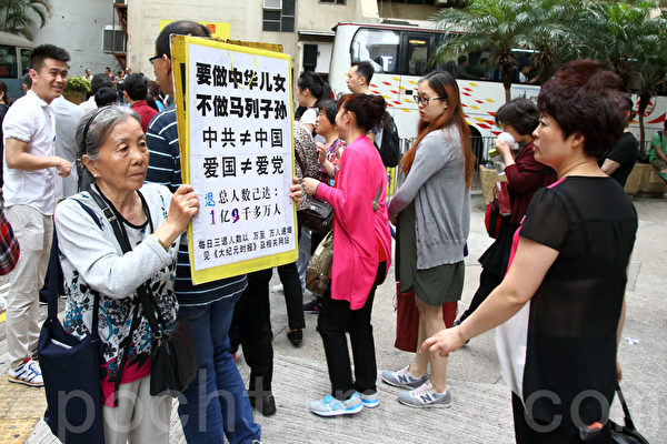 近几年,每年访港的大陆游客超过4千万人次,许多人在旅游景点纷纷了解法轮功真相和进行三退,图为图为法轮功学员席大姐拿展板向大陆游客劝三退。(潘在殊/大纪元)
