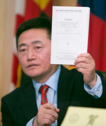 李祥春手举美国国会及行政当局中国委员会的报告,其中收录了他提交的中国退党大潮报告。(李莎/大纪元)